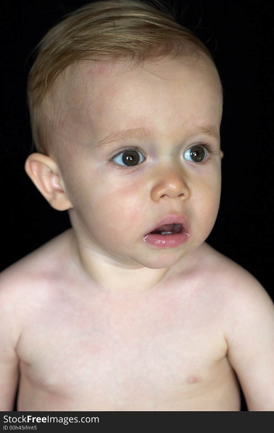 Image of beautiful toddler sitting in front of a black background