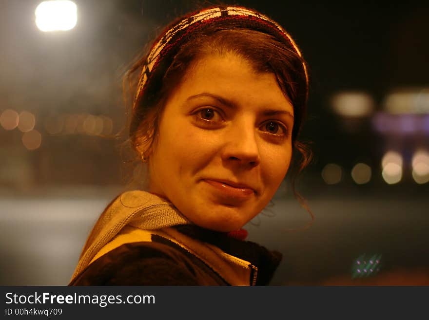 Young woman smiling at street. Cold winter night.