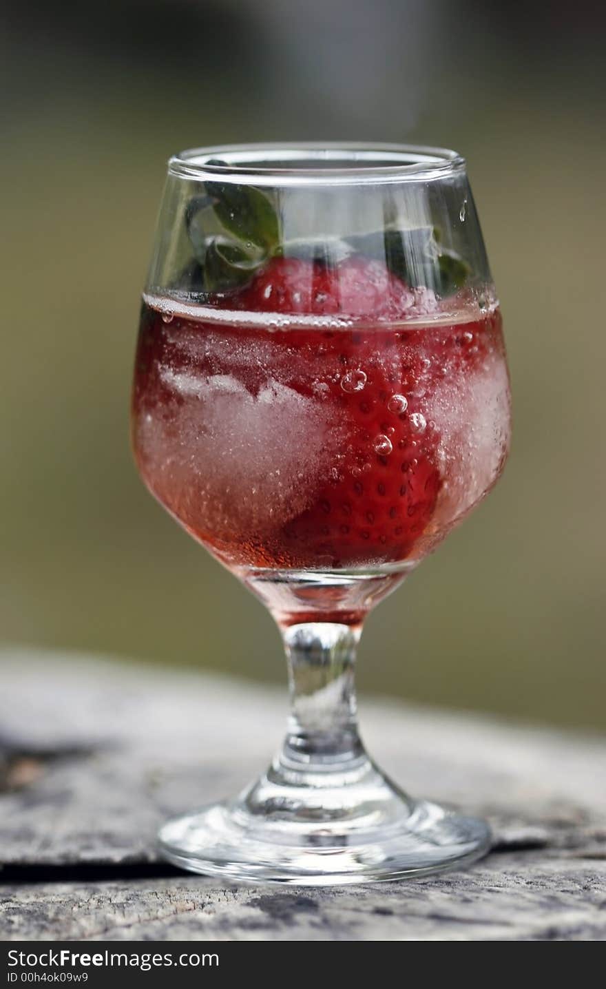 Single strawberry in glass against a natural background. Single strawberry in glass against a natural background