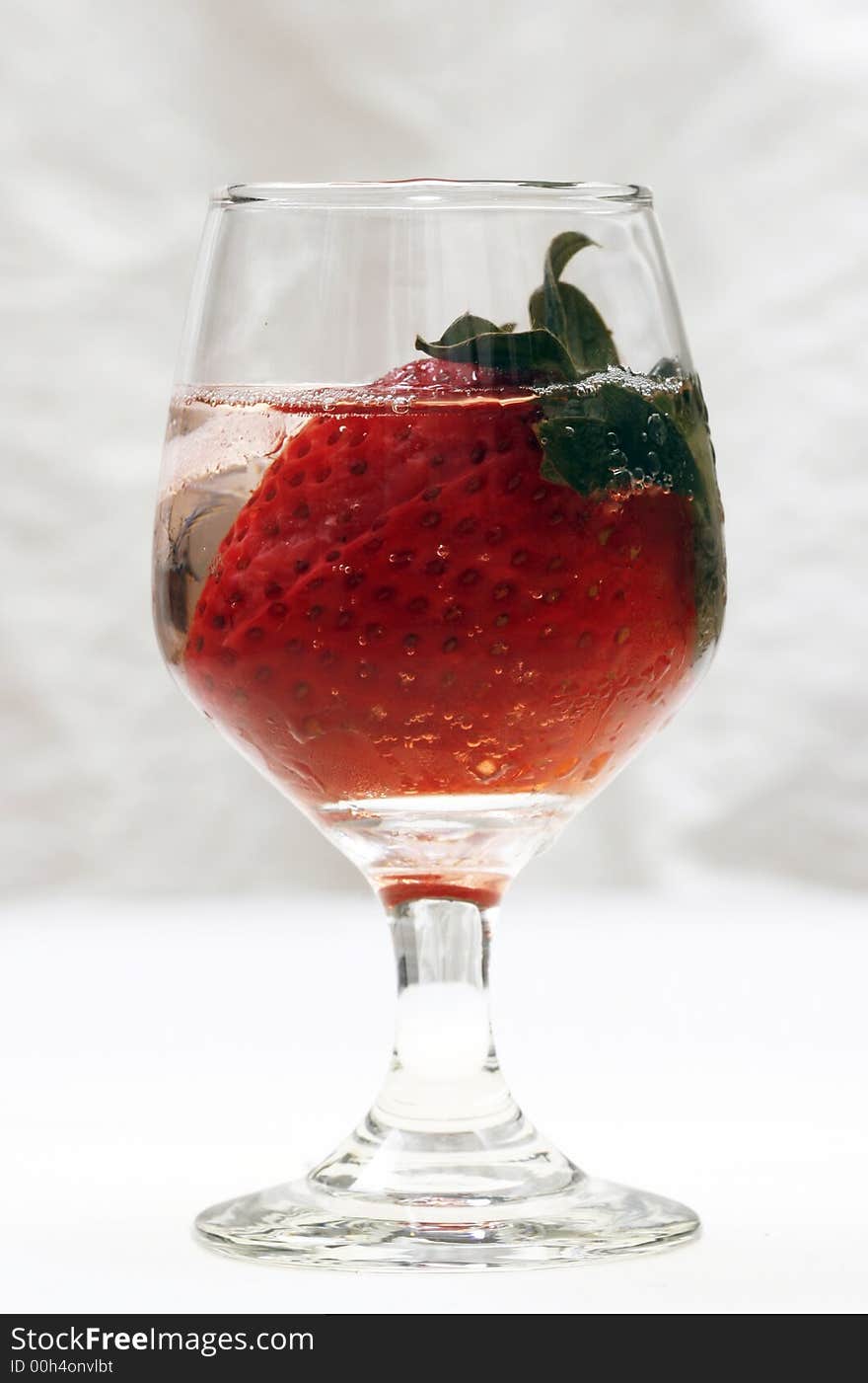 Single strawberry in a glass with ice on white background. Single strawberry in a glass with ice on white background