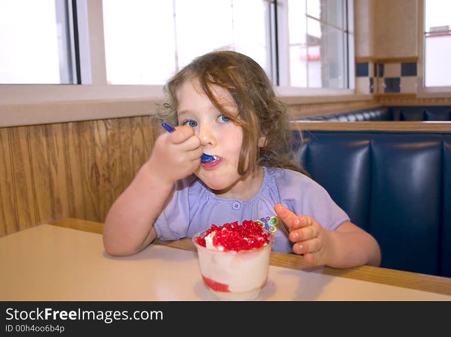 A little girl eating icecream in a restaurant. A little girl eating icecream in a restaurant