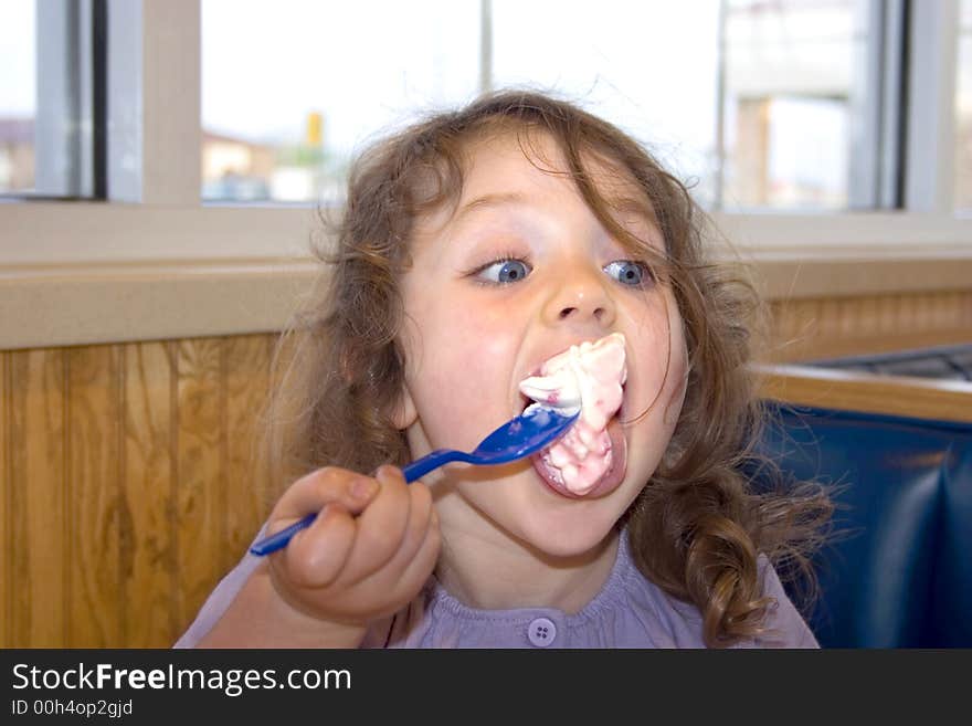 A young girl with a big spoonful of ice cream. A young girl with a big spoonful of ice cream