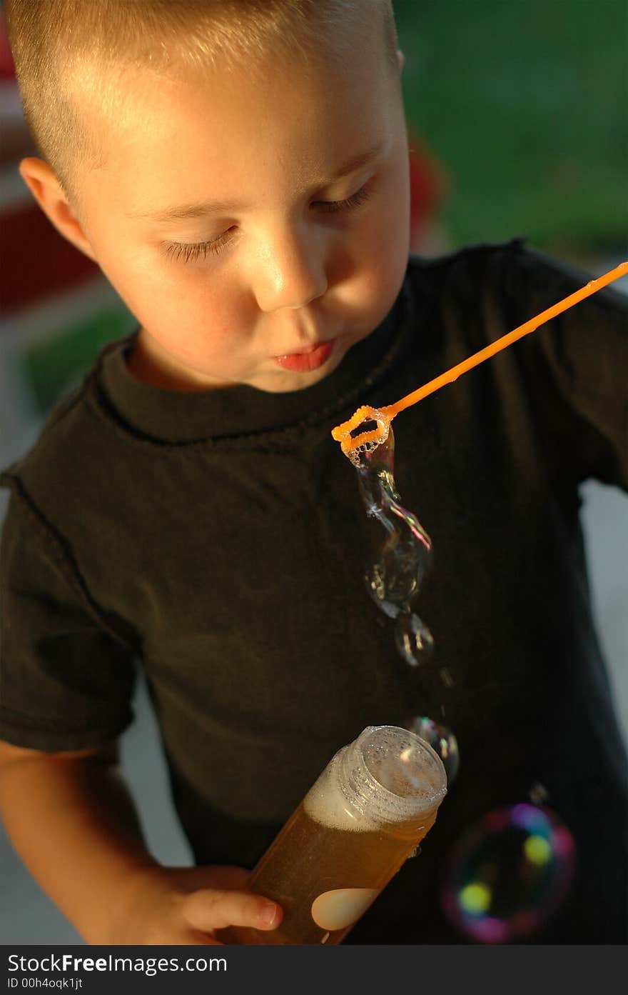 Young boy blowing bubbles at dusk on a summer day