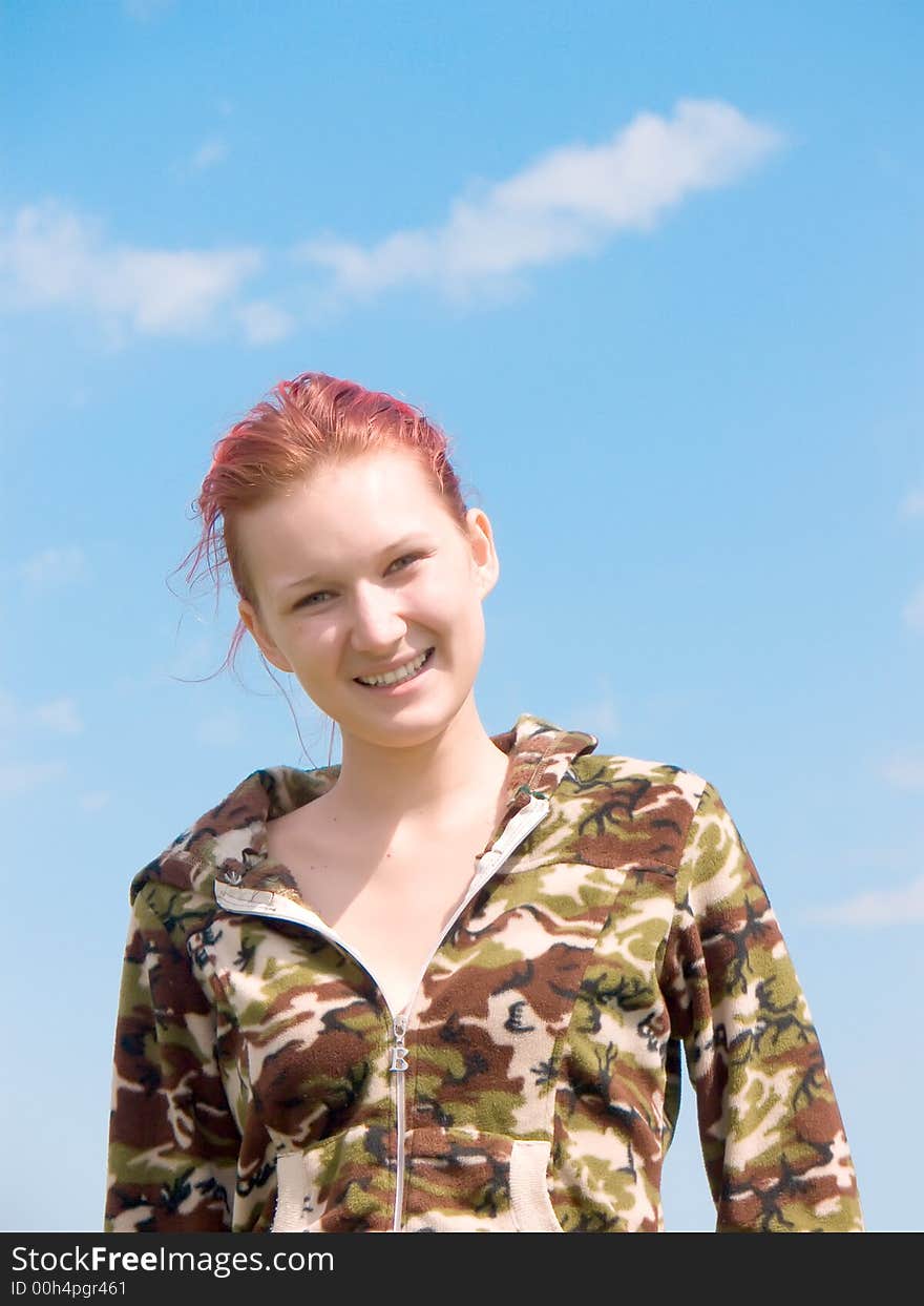 Photograph of the young girl in a jumper of color of a camouflage on a background of the sky