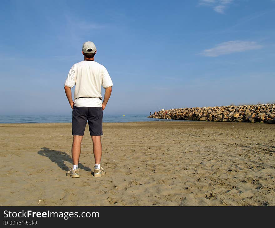 Man looking at the sea standing on the beach. Man looking at the sea standing on the beach