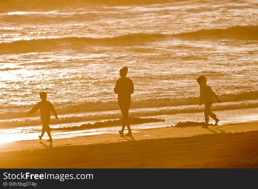 A woman with her two children walking along the beach. A woman with her two children walking along the beach.