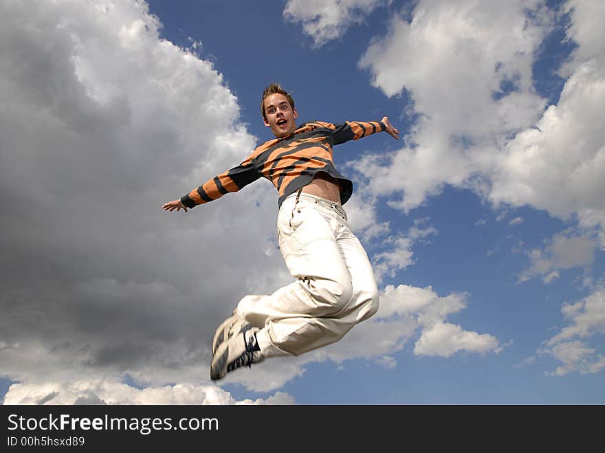 Young man happily jumping against blue sky. Young man happily jumping against blue sky.