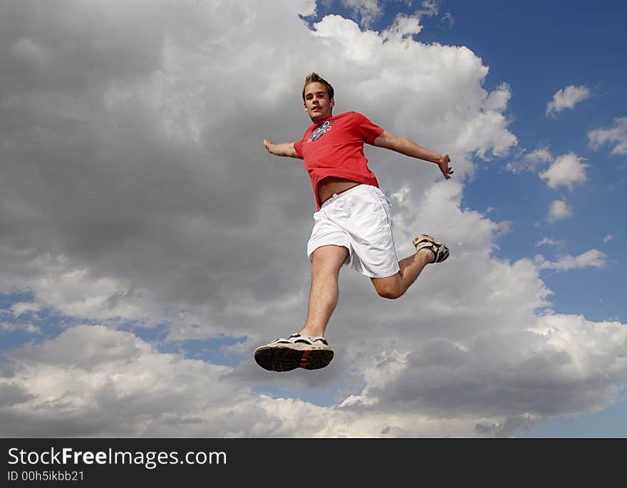 Young man happily jumping against blue sky. Young man happily jumping against blue sky.