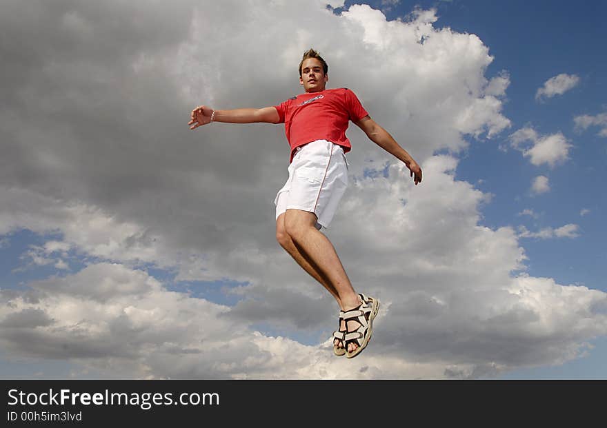 Young man happily jumping against blue sky. Young man happily jumping against blue sky.