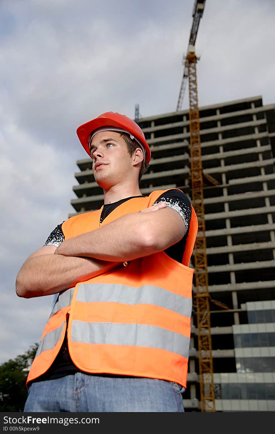 Construction supervisor in safety helmet and reflex vest in front of construction site.