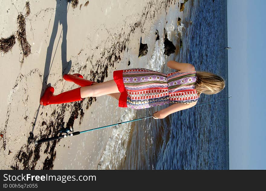 A beautiful young woman with a fishing pole walking along shore line. A beautiful young woman with a fishing pole walking along shore line