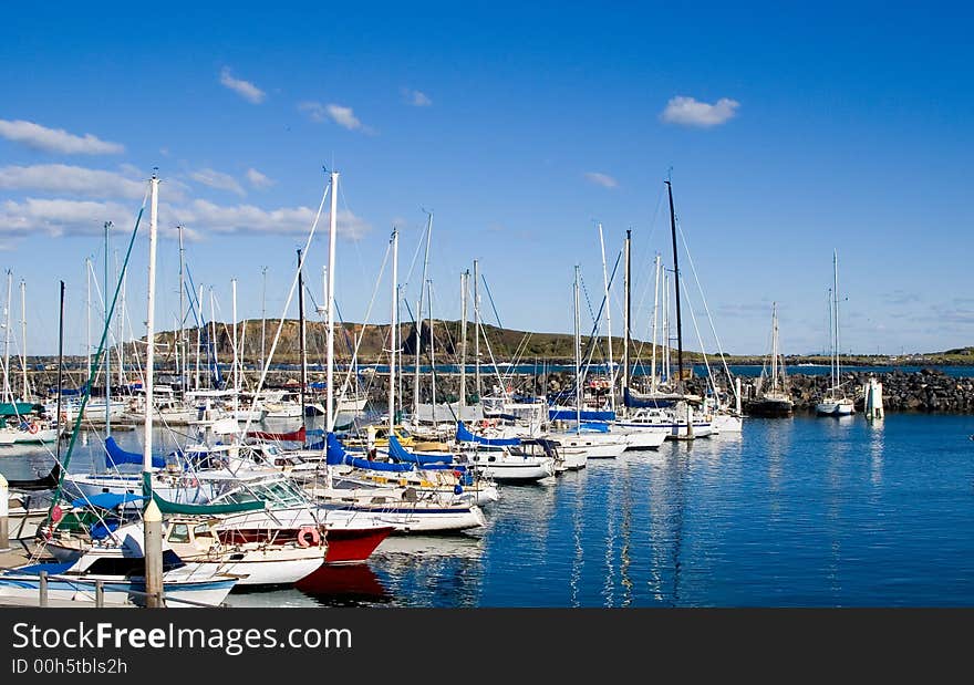 A group of sailing boats moored in a harbour with reflections on the water. A group of sailing boats moored in a harbour with reflections on the water.