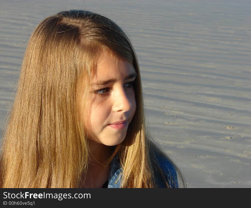 Young girl standing on the beach, looking into the distance