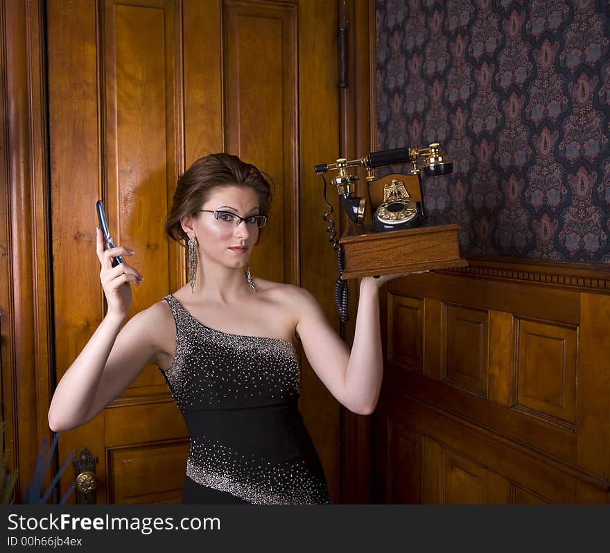 Beautiful young brunette woman wearing an evening gown holding an old fashioned telephone in one hand and a modern cell phone in the other. See my portfolio for more like this. Beautiful young brunette woman wearing an evening gown holding an old fashioned telephone in one hand and a modern cell phone in the other. See my portfolio for more like this.