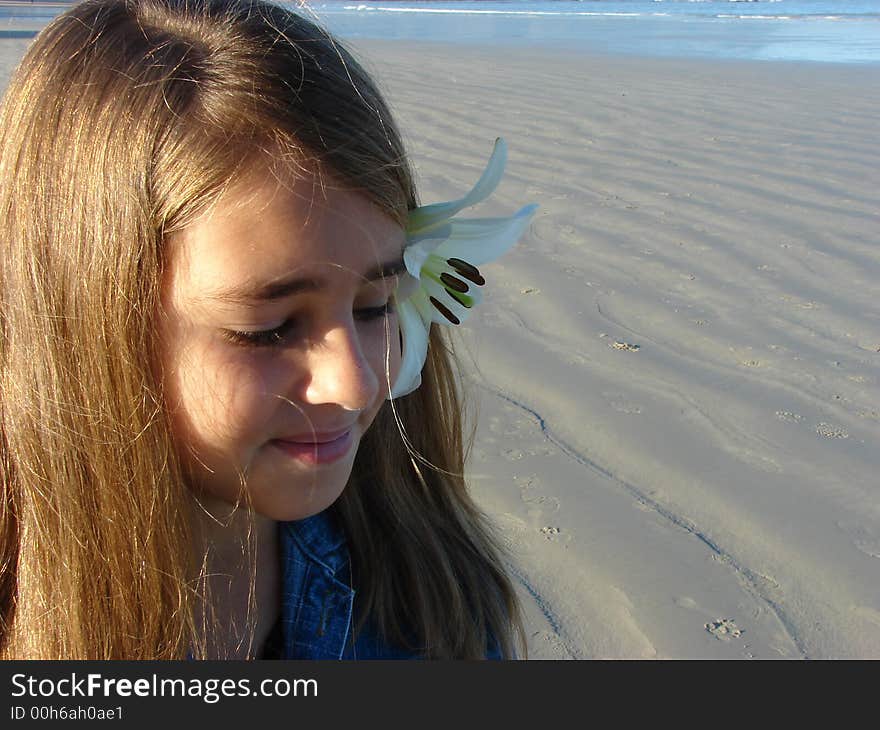 Young girl sitting on the beach with a flower in her hair. Young girl sitting on the beach with a flower in her hair