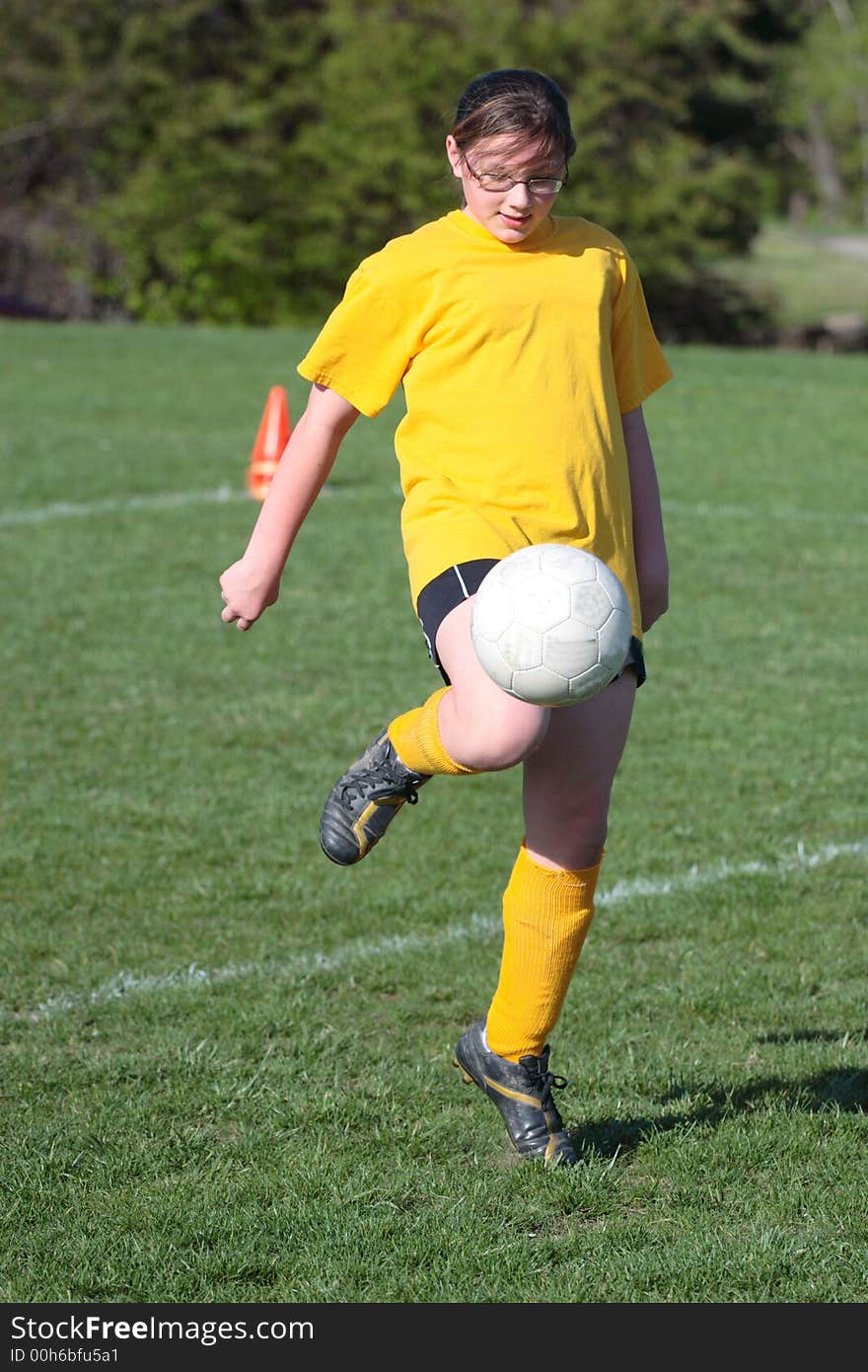 Girl using knee to move soccer ball down the field. Girl using knee to move soccer ball down the field.