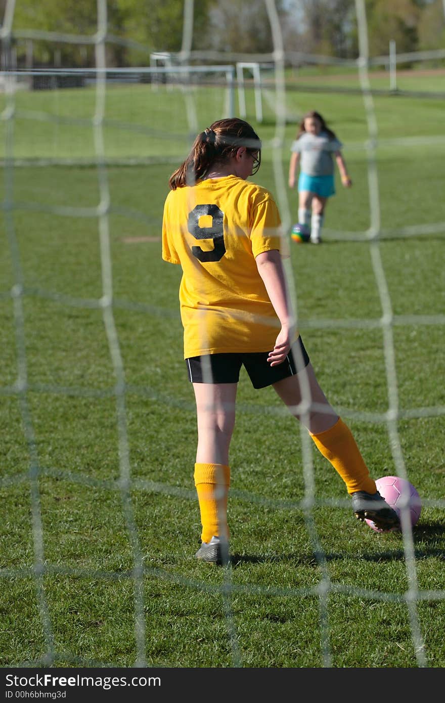 Girl kicking ball at soccer field practice in goalie pen. Girl kicking ball at soccer field practice in goalie pen.