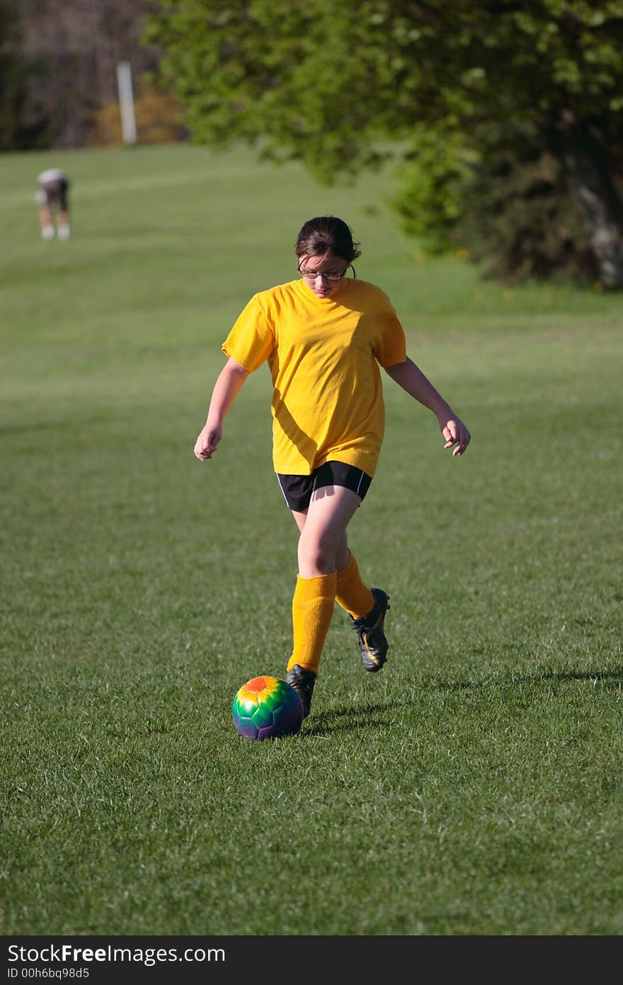 Girl kicking ball at soccer field during a game. Girl kicking ball at soccer field during a game.