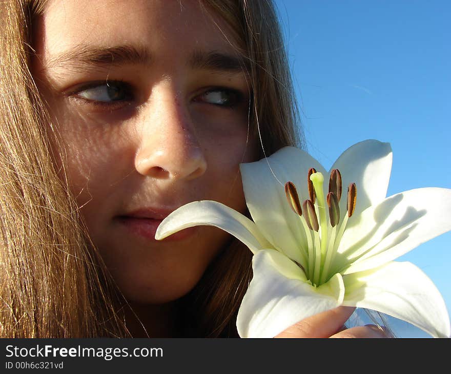 Young girl with a flower close to her face, Head & Shoulders Shot. Young girl with a flower close to her face, Head & Shoulders Shot