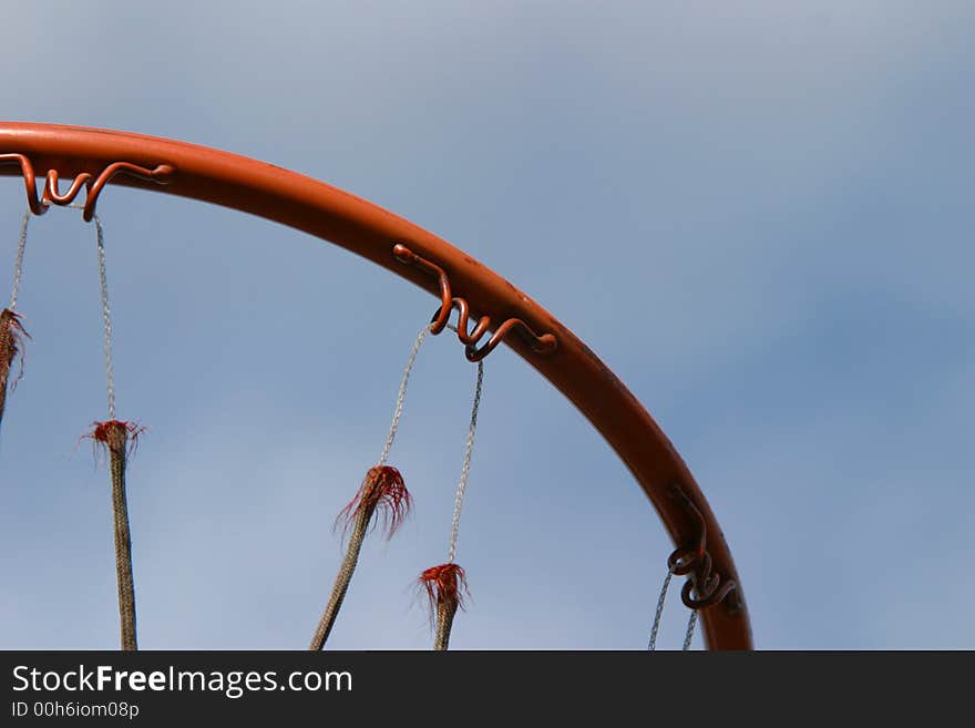 The ring of a basketball hoop. The net is very well worn and old. The ring of a basketball hoop. The net is very well worn and old.