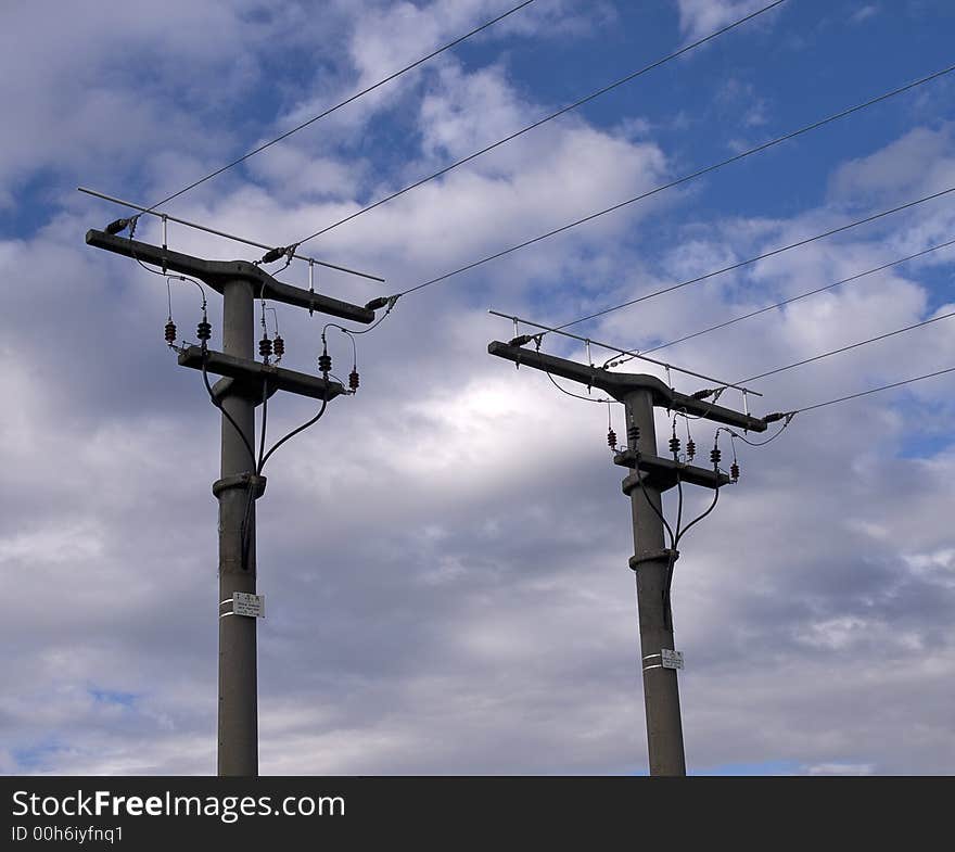 Electric pylons with the wires in front of blue sky with white clouds. Electric pylons with the wires in front of blue sky with white clouds