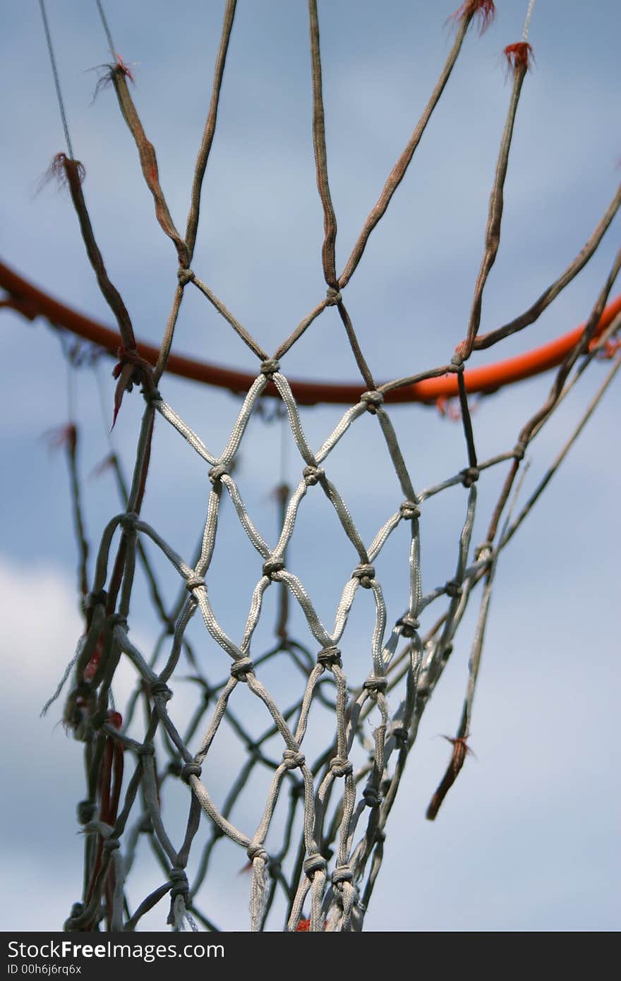 A basketball loop with an old and worn net.