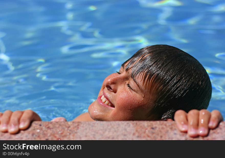 Young boy with eyes closed, smiling enjoying the sun in a swimming pool. Young boy with eyes closed, smiling enjoying the sun in a swimming pool