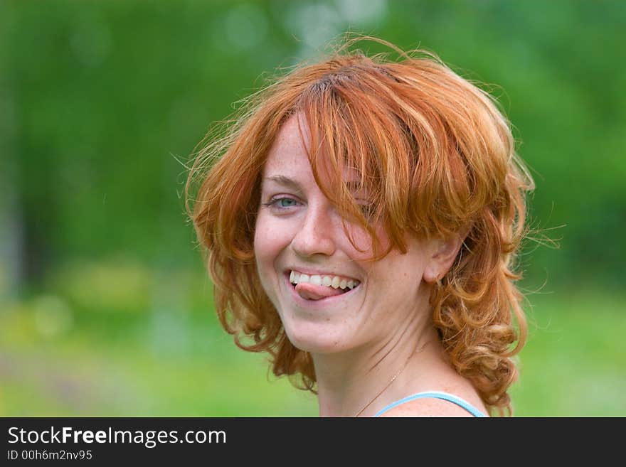 Outdoor shot of red-haired girl who put out tongue. Outdoor shot of red-haired girl who put out tongue