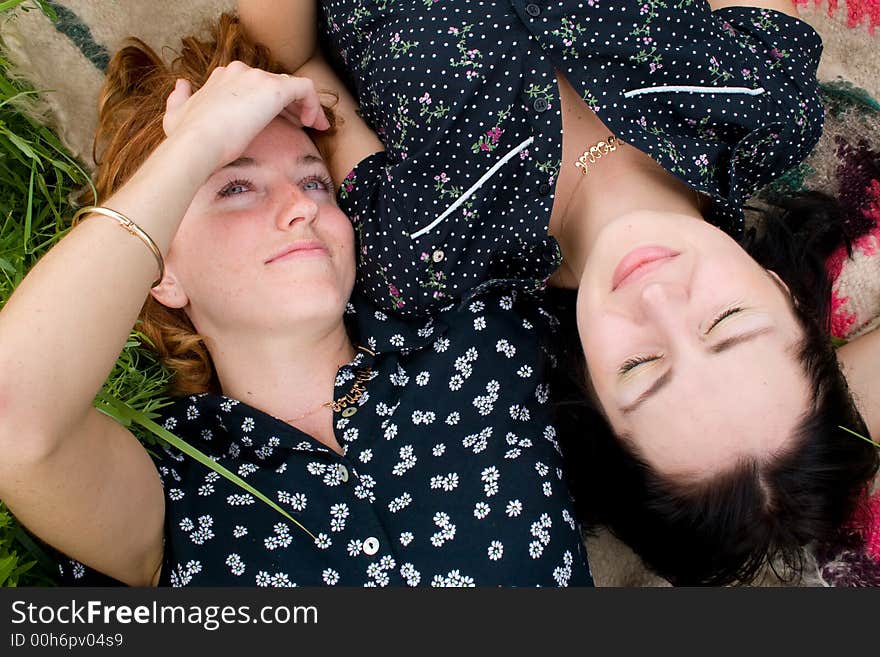 Girls lying on meadow, one of them are looking upward, one has eyes closed