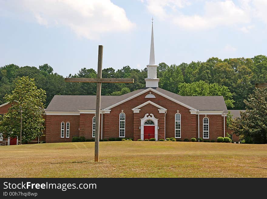 A church with a cross in the field out front. A church with a cross in the field out front