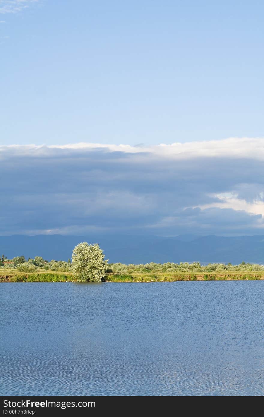 String of land between water and blue stormy skies - unreal lighting landscape. String of land between water and blue stormy skies - unreal lighting landscape