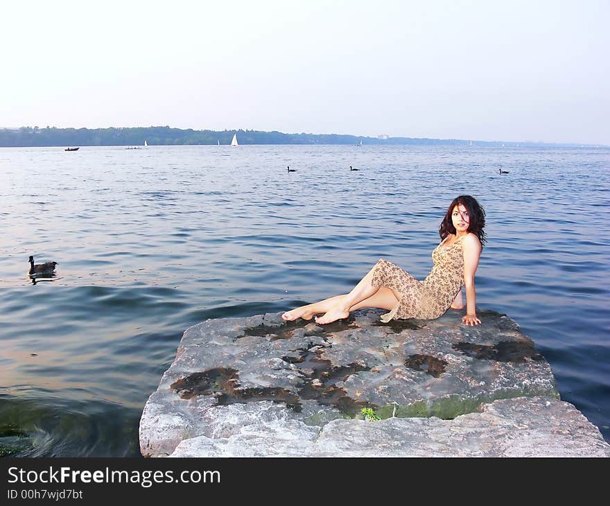 A young girl sitting on a big rock in the lake Ontario, resting and enjoying the
peace and quietness of the water. A young girl sitting on a big rock in the lake Ontario, resting and enjoying the
peace and quietness of the water.