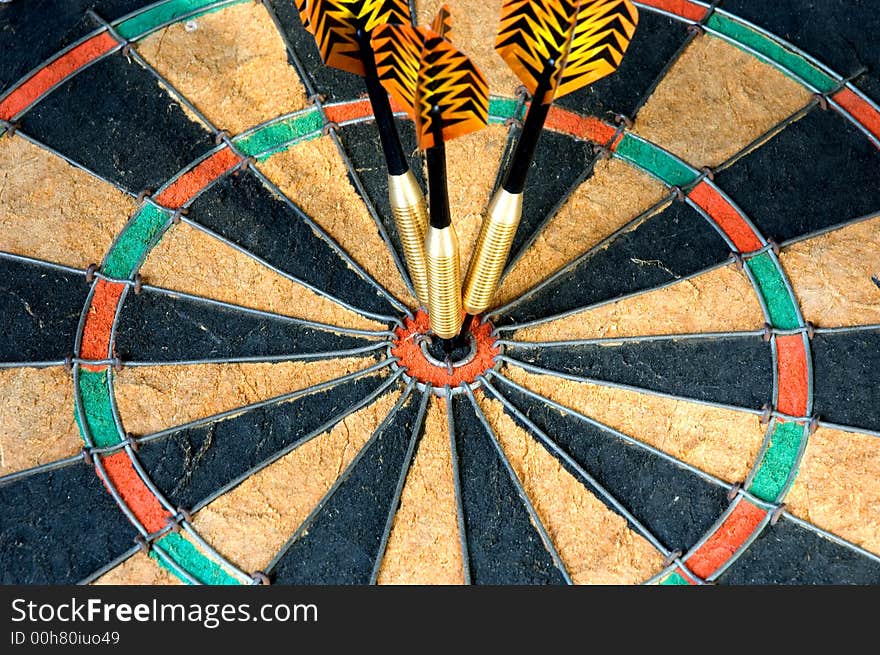 Three darts hitting the bullseye on a dart board