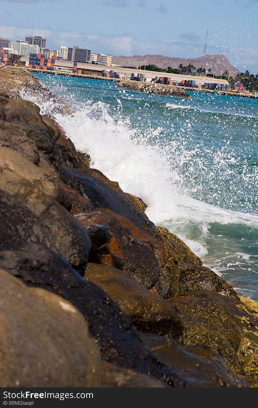 Wave Splash against rocks with Honolulu Diamond Head crater in the background