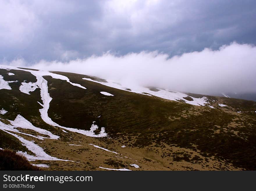 War of elements. Clouds swim above mountains