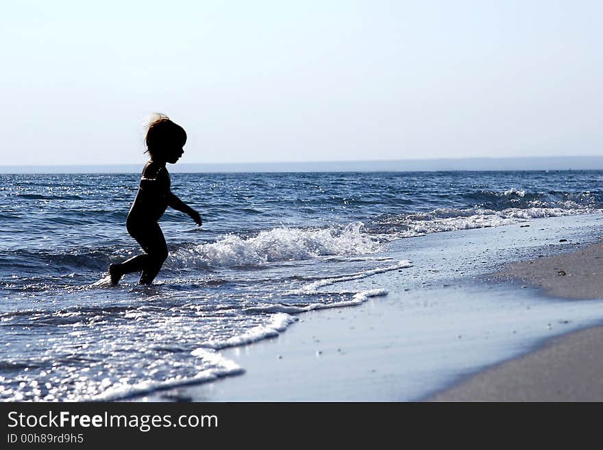 Silhouette of running baby in the sea