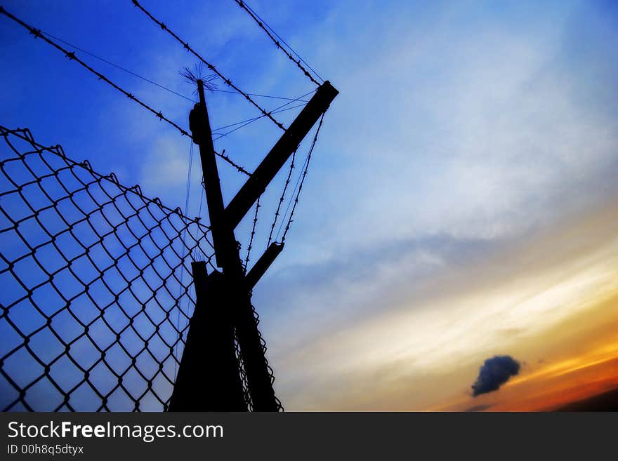 A fence used as a security in silhouette during sunset . A fence used as a security in silhouette during sunset .