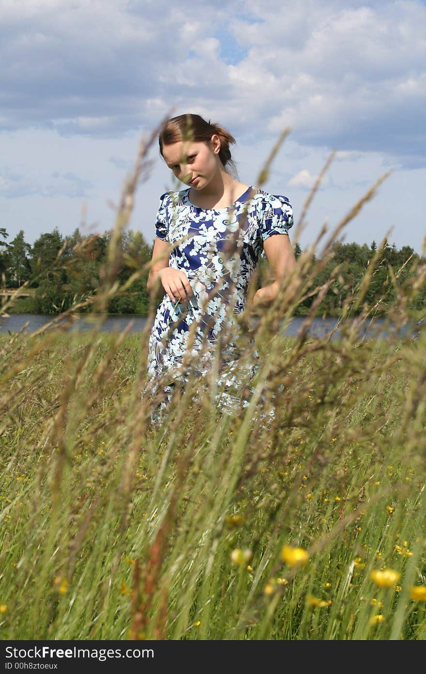 Young beautiful girl sitting on the grass in the field in summer warm day. Young beautiful girl sitting on the grass in the field in summer warm day