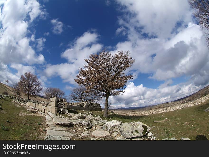 Tree alone u8nder blue cloudly sky with ancient ruins. Tree alone u8nder blue cloudly sky with ancient ruins