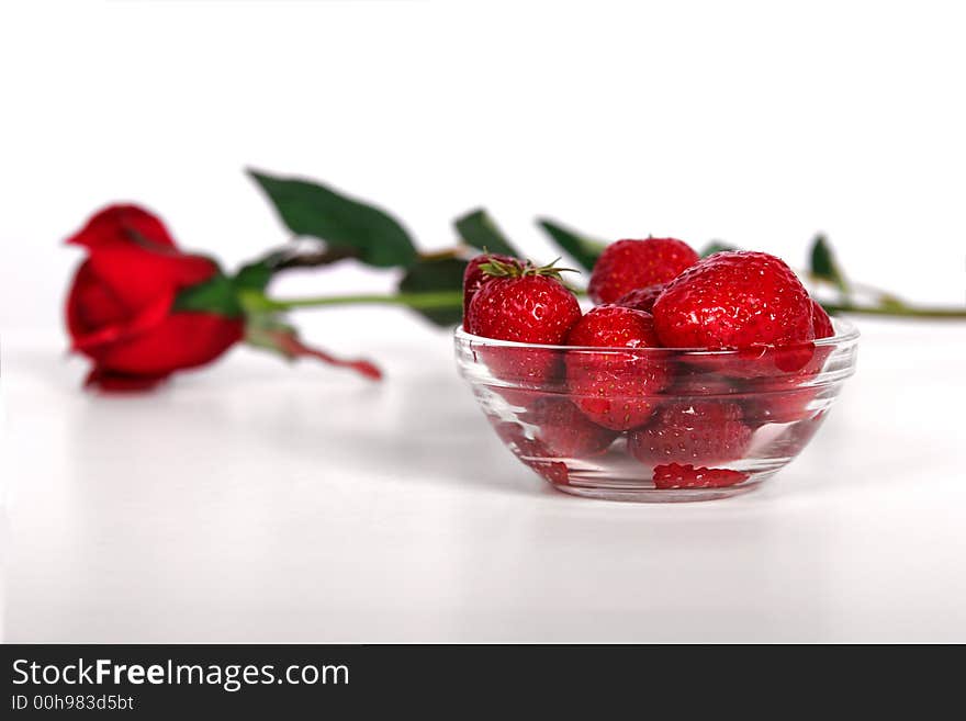 A bowl of fresh strawberries and a single red rose. A bowl of fresh strawberries and a single red rose.