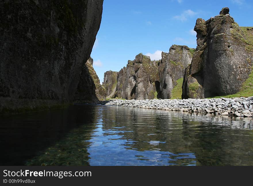 Magnificent scenic from inside a river canyon in southern Iceland, cliffs on all sides, and blue sky above