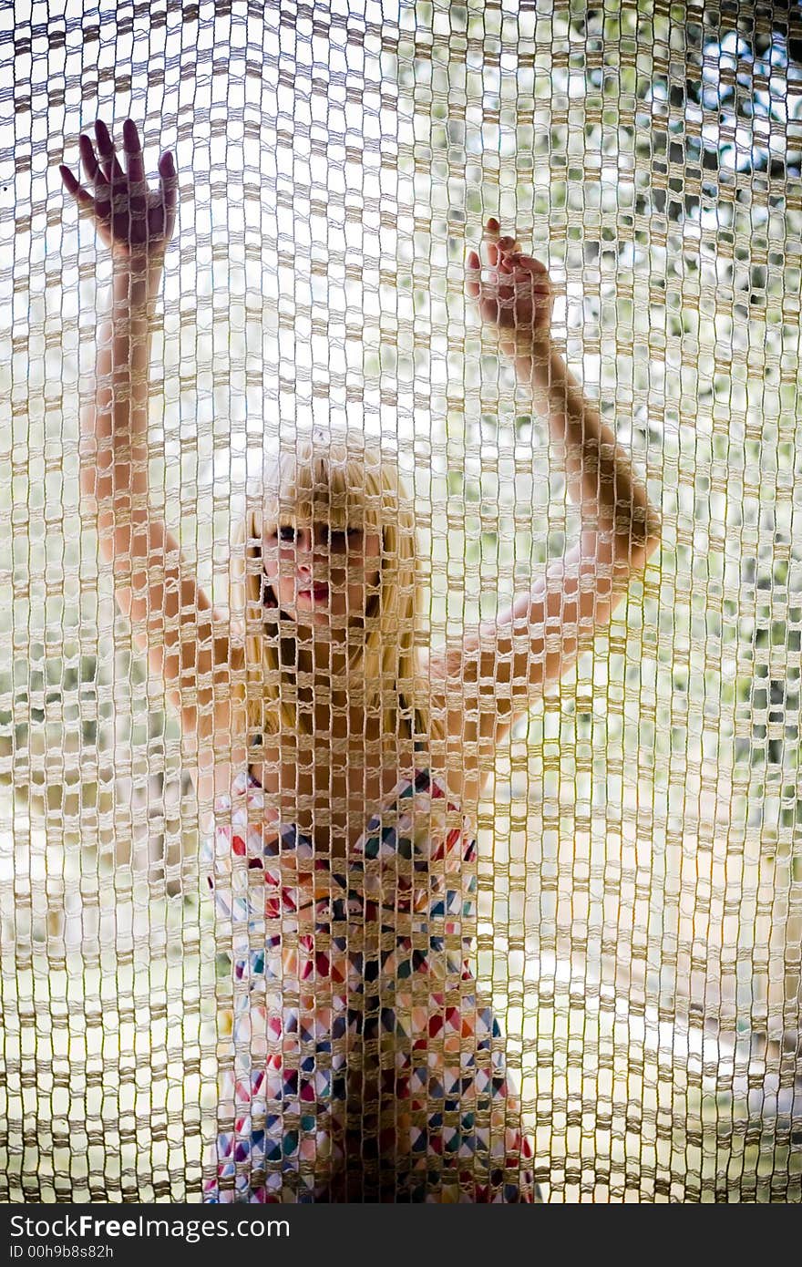 Young blonde girl behind a net