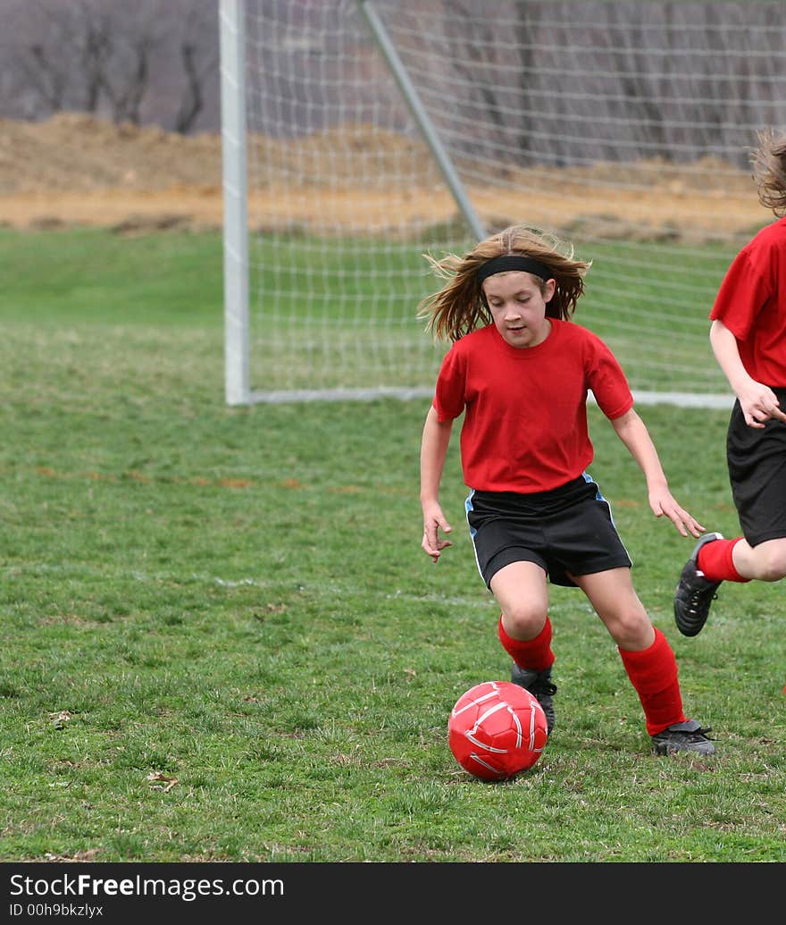 Girl kicking ball at soccer field during a game. Girl kicking ball at soccer field during a game.