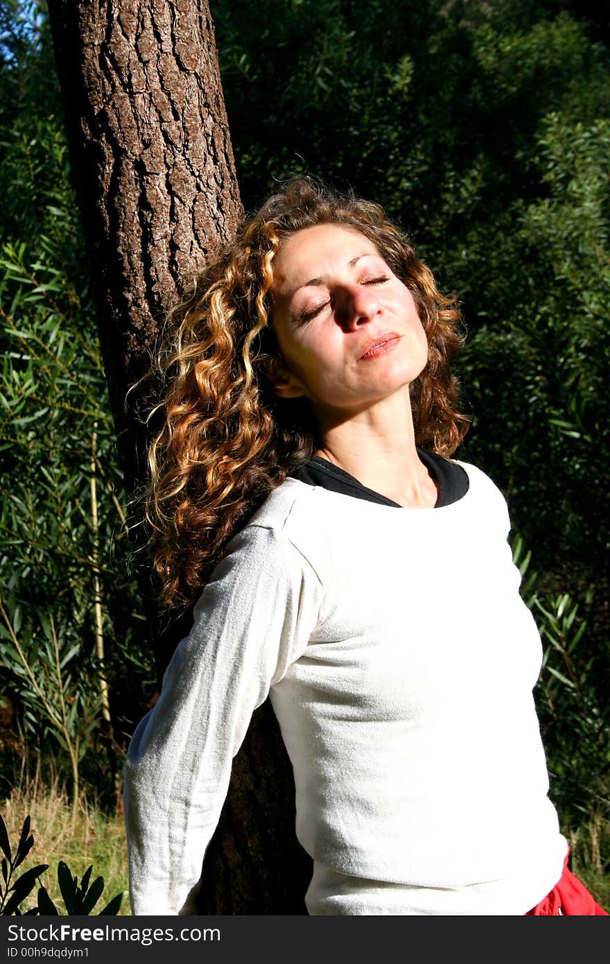 Digital photo of a woman leaning against a tree.