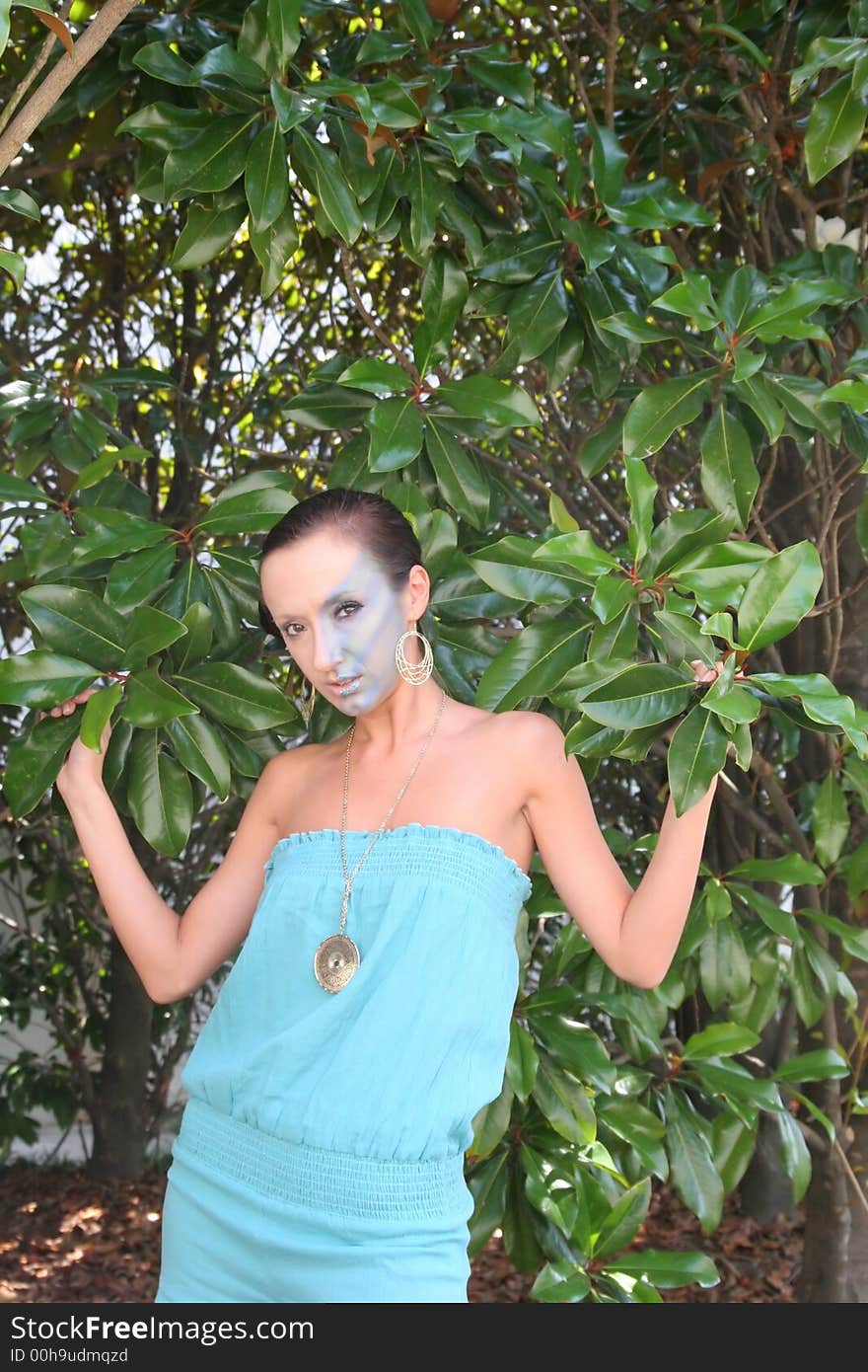 A fashion makeup model in blue dress and trees. A fashion makeup model in blue dress and trees