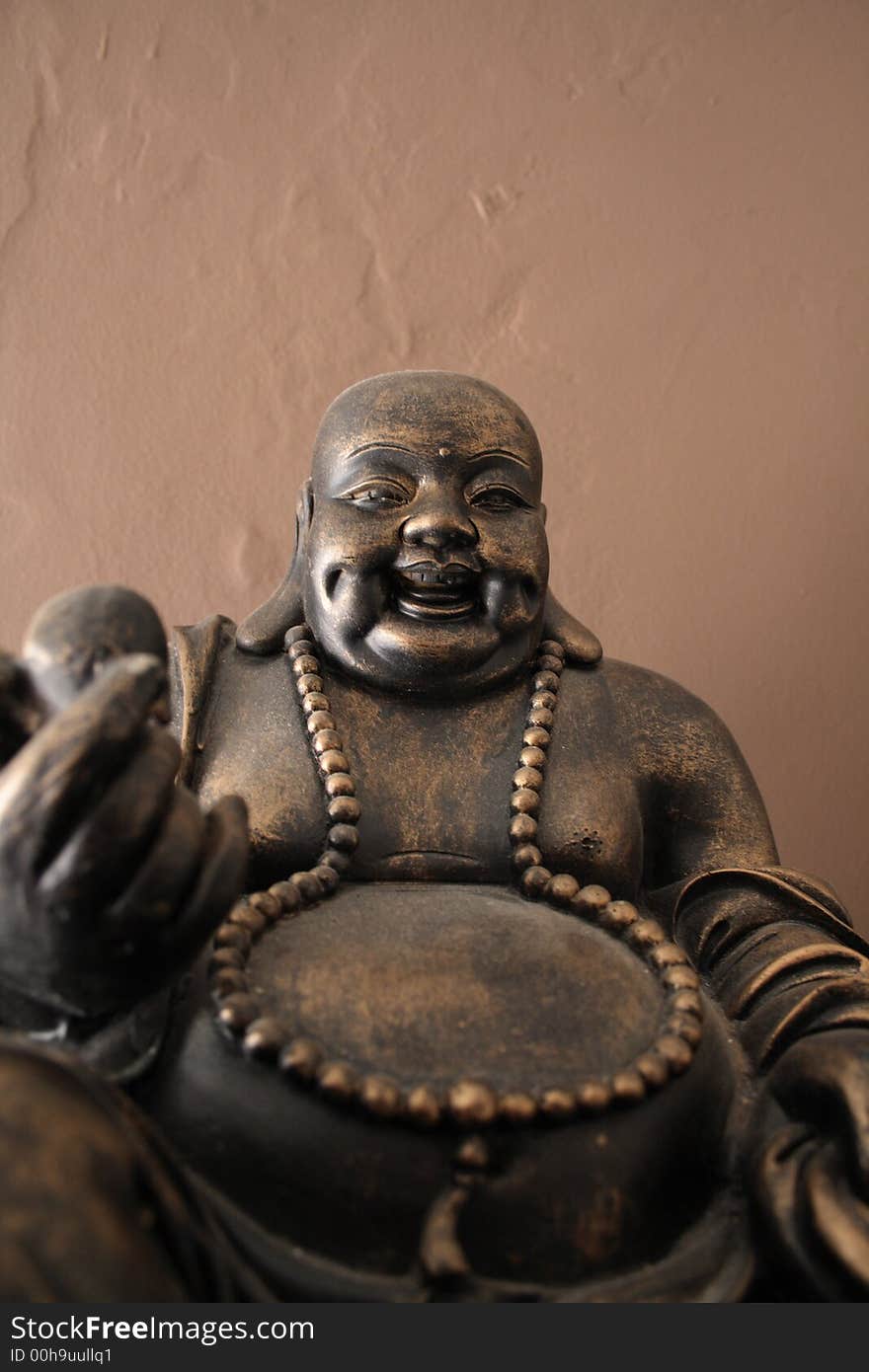 Bronze statue of budha with old wall in background