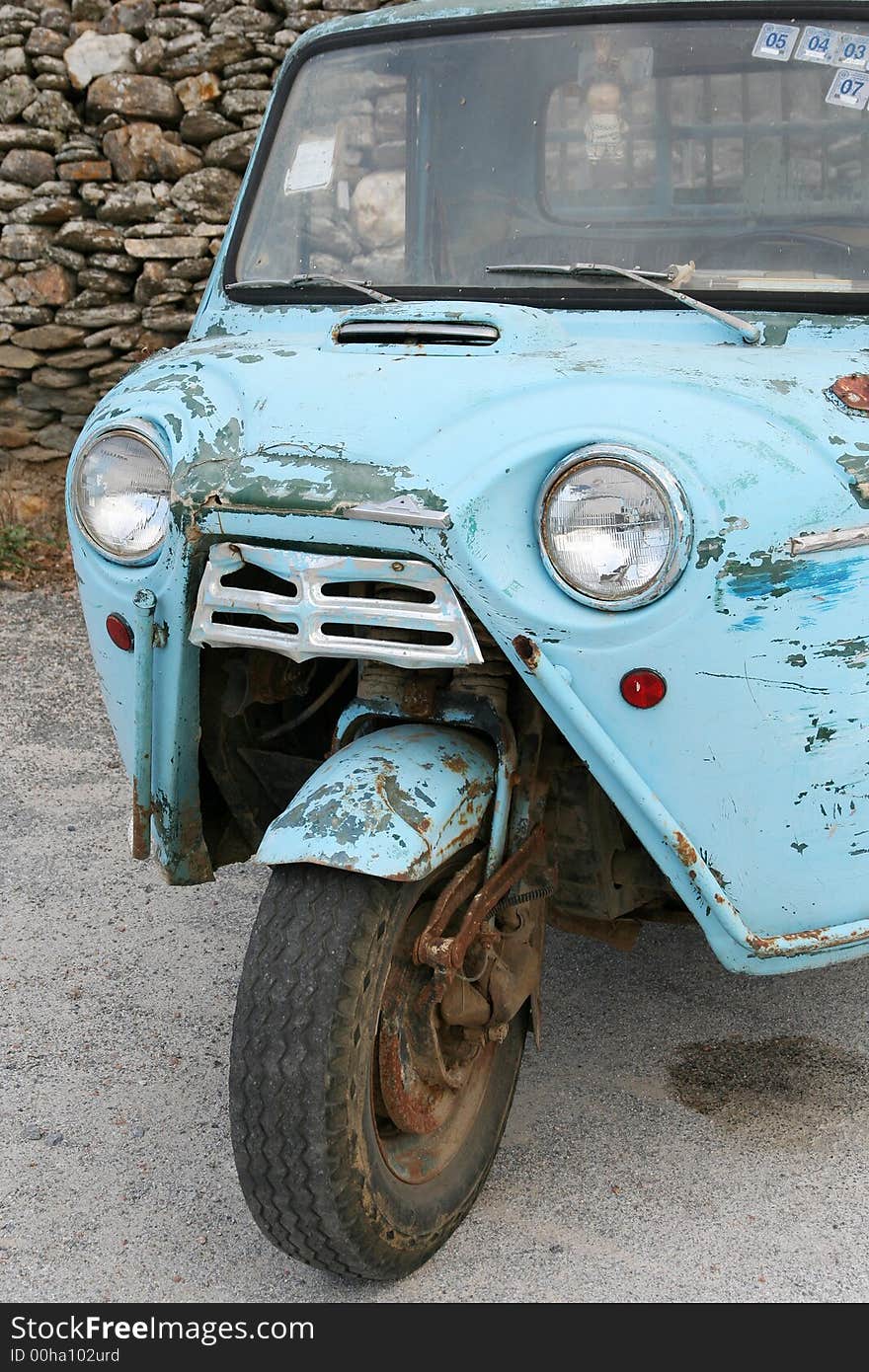 An old tricycle motorcycle parked in a lot. An old tricycle motorcycle parked in a lot