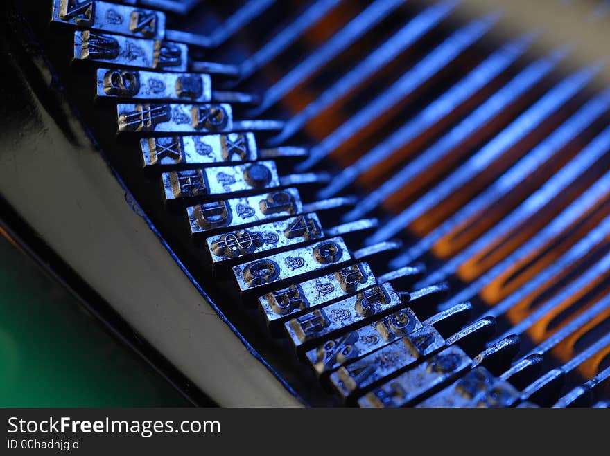 Medium closeup of vintage typewriter typebar with limited depth of field and lit with blue and orange lights. Medium closeup of vintage typewriter typebar with limited depth of field and lit with blue and orange lights