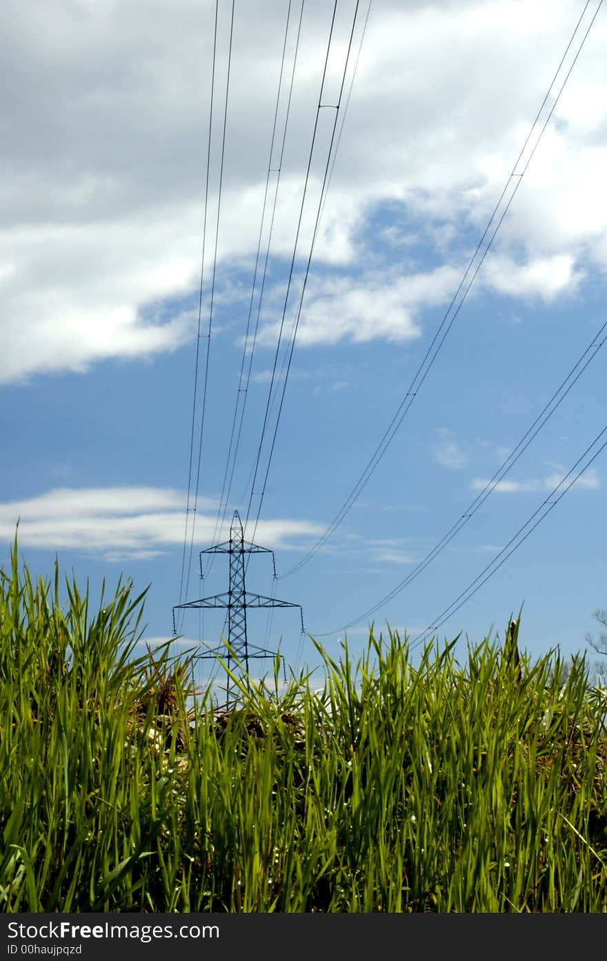 Taken from a low angle, electricity pylons seem to rise out of lush green grass. Taken from a low angle, electricity pylons seem to rise out of lush green grass.