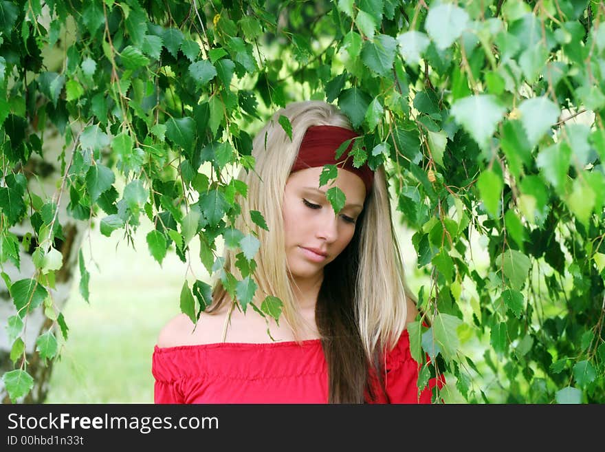 Outdoor beauty portrait of a young smiling woman in nature against a tree